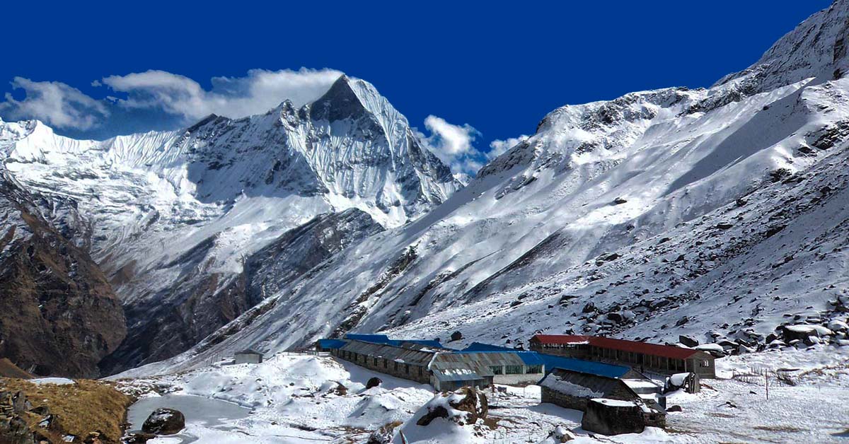 A snowy mountain with buildings in Annapurna base Camp 